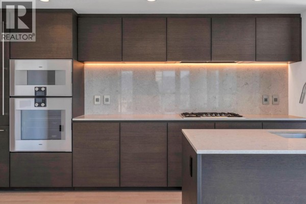Contemporary kitchen featuring dark cabinetry, marble backsplash, and built-in appliances - 1303 1408 Robson Street, Vancouver