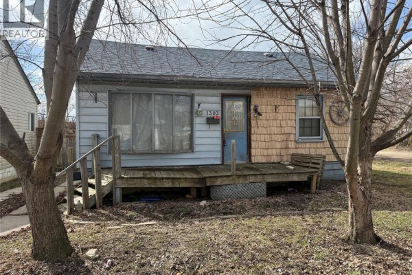 House exterior with deck, blue door, and decorative wagon wheel - 1303 Central Windsor