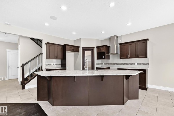View from the stairs looking into the open-concept living area with a kitchen island. - 13032 208 St Nw, Edmonton