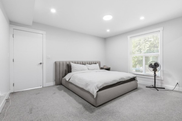 Grey carpeted bedroom with king-size bed and large window. - 13035 98a Avenue, Surrey