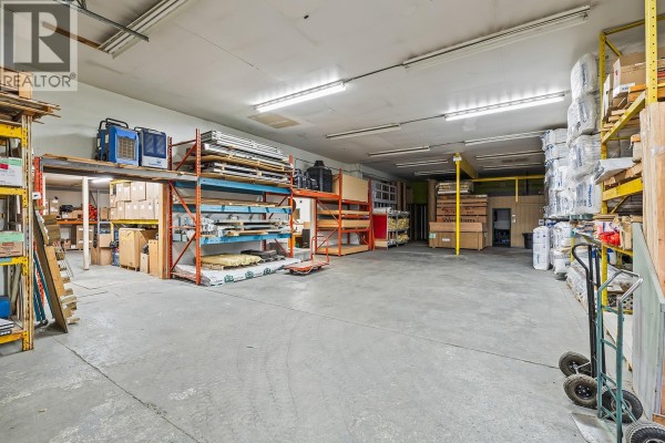Interior warehouse space with shelving units, stored goods, concrete floor, and fluorescent lighting. - 1304, 1320, 1334 Industrial Road, West Kelowna
