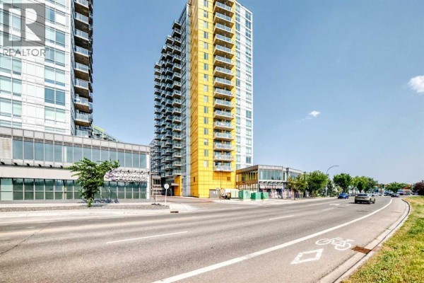 Street view of modern apartment buildings with glass balconies and a yellow accent facade. - 1304, 3820 Brentwood  Nw, Calgary