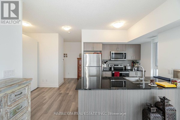 Modern kitchen with stainless steel appliances, granite countertops, and wood cabinetry. - 1304 - 1604 Eglinton Avenue W, Toronto