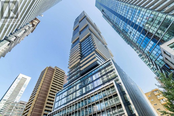 Low-angle view of a tall skyscraper surrounded by other high-rise buildings against the sky. - 1304 - 55 Charles Street E, Toronto
