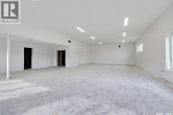 Interior view showing an open space with white panel walls and an adjoining room. - 1304 Hamilton Street, Regina