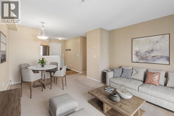 Dining area with a round table and four chairs, adjacent to the living room. - 1305, 8 Bridlecrest Drive Sw, Calgary