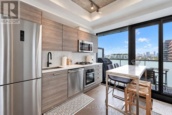 Modern kitchen with stainless steel appliances, grey cabinetry, and a marble-topped island with bar stools. - 1305 - 11 Charlotte Street, Toronto