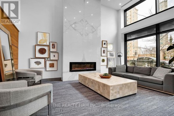 Building lobby with a large fireplace, artwork on the wall, and comfortable seating. - 1305 - 505 Talbot Street, London East