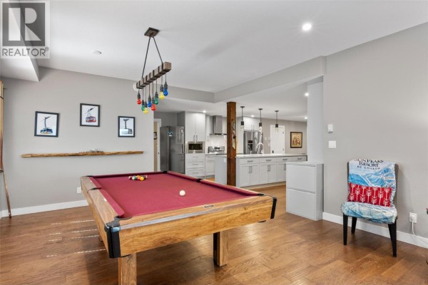 Primary bedroom with queen bed, armchair, and ensuite bathroom with glass shower and tiled walls. - 1305 Burfield Drive Unit# 1, Sun Peaks