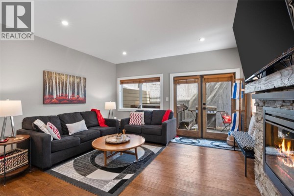 Outdoor patio with hot tub, gas grill, seating area, red table, and concrete wall. - 1305 Burfield Drive Unit# 1, Sun Peaks