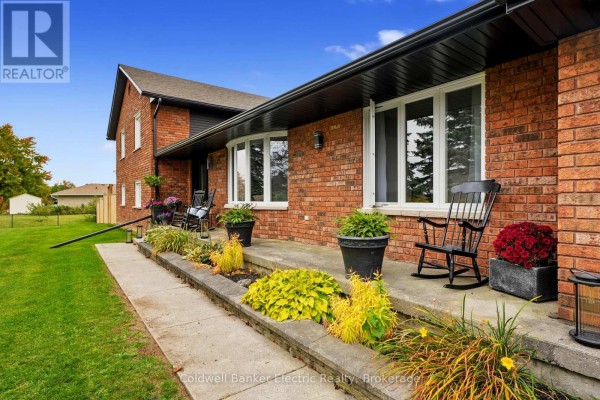Close-up of the house's brick facade showing a covered porch with rocking chairs. - 1305 Holden Road, Selwyn