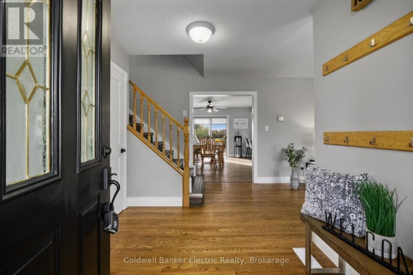 View of the entryway with wood floors, staircase, and a glimpse into the dining area. - 1305 Holden Road, Selwyn