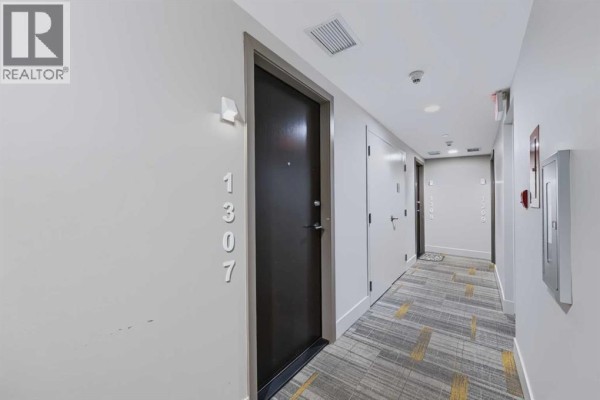 Apartment building hallway with a dark brown door, numbered 1307. - 1307, 901 10 Avenue Sw, Calgary