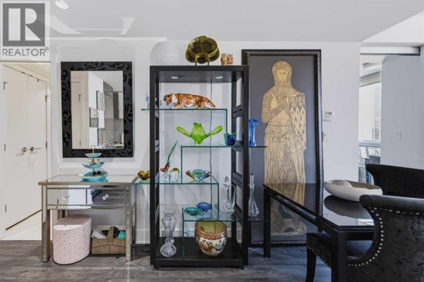 Living room with glass display cabinet, mirrored table, and artwork. - 1307, 901 10 Avenue Sw, Calgary