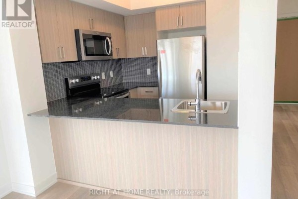 Kitchen island with sink and seating area, adjacent to stainless steel appliances and cabinets. - 1308 - 1603 Eglinton Avenue W, Toronto