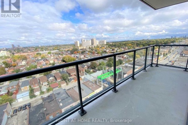 Balcony view from apartment with glass railing overlooking a city skyline and suburban rooftops. - 1308 - 1603 Eglinton Avenue W, Toronto