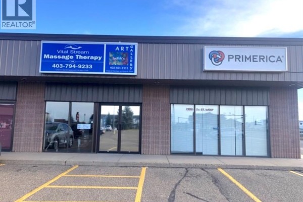 Storefronts with signs for Vital Stream Massage Therapy, Art Gallery, and Primerica. - 1308 2a Street W, Brooks