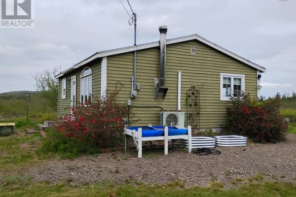 Side view of the green bungalow with large arched window, red fire hydrant, and wooden gate. - 1308 Cape D'or Road, Advocate Harbour