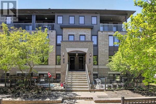 Exterior of the modern townhouse complex with brick and dark siding, surrounded by trees. - 130a Lindenshade Drive, Ottawa
