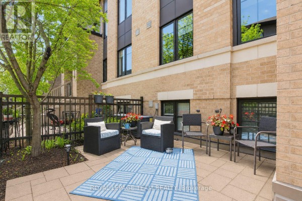 Ground level patio area with outdoor furniture, planters, and a blue checkered rug. - 130a Lindenshade Drive, Ottawa