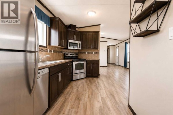 Kitchen area with dark wood cabinets, granite countertops, and stainless steel appliances. - 131, 8010 100 Street, Grande Prairie