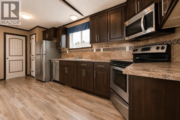 Kitchen features dark brown cabinets, speckled countertops, and stainless steel appliances. - 131, 8010 100 Street, Grande Prairie