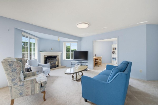View of the living and dining area with light blue walls, carpet, and large windows. - 131 1450 Mccallum Road, Abbotsford