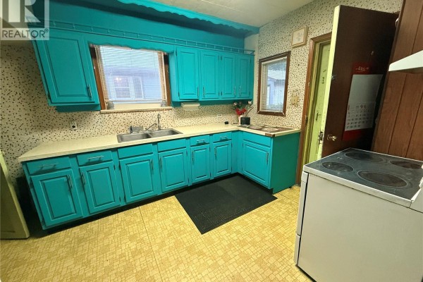 Kitchen with bright teal cabinets, a white countertop, and a white stove. - 131 2nd Avenue W, Biggar