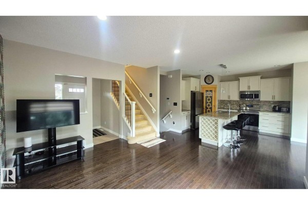 Open concept living area and kitchen with dark wood floors and light grey walls. - 131 57 St Sw, Edmonton