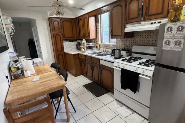 Kitchen with wood cabinets, white tile flooring, stainless steel refrigerator, and gas stove. - 131 Cameron Avenue, Toronto