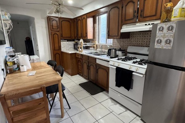 Kitchen with wood cabinets, white tile flooring, stainless steel refrigerator, and gas stove. - 131 Cameron Avenue, Toronto