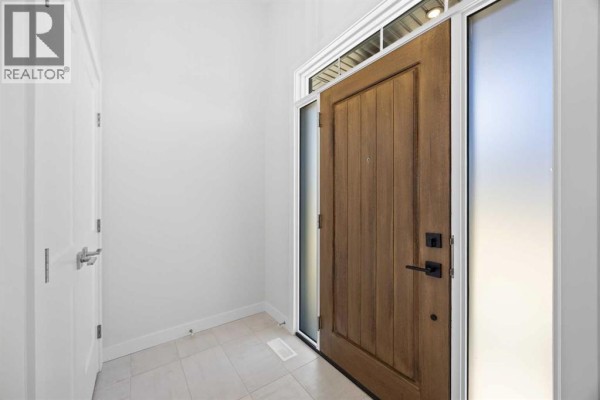Entrance foyer with a tall wooden front door, frosted glass side panels, and a closet. - 131 Greenwich Drive Nw, Calgary