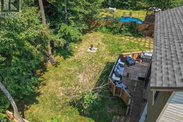 Aerial view of a wooden deck with outdoor seating, a barbecue, and a grassy backyard with a pool. - 131 Meadow Park Cres, Sault Ste  Marie