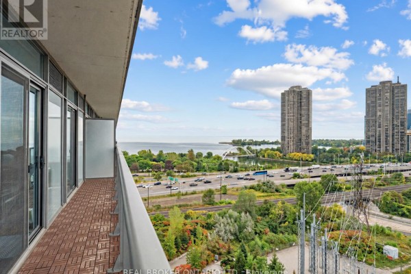 Balcony with wooden deck tiles and a view of Lake Ontario, city buildings, and a highway. - 1310 - 105 The Queensway, Toronto