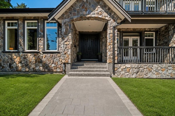 Close-up of the stone exterior and double dark wood front doors with a covered porch. - 13101 14 Avenue, Surrey