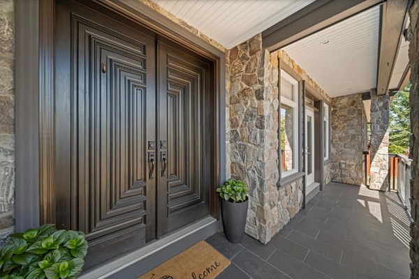 Detailed view of the ornate double front doors and stone facade with a potted plant. - 13101 14 Avenue, Surrey