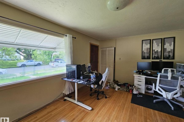 Interior of a room with a large window, hardwood floors, and multiple computer workstations. - 13103 63 St Nw Nw, Edmonton