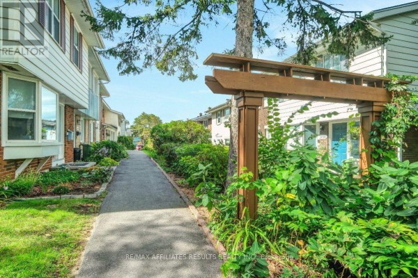 Pathway leading past townhouses with green landscaping and mature trees. - 1312 Cornell Street, Ottawa