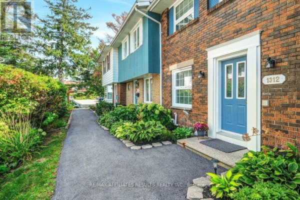 Exterior view of brick townhouses with blue accents and landscaped walkways. - 1312 Cornell Street, Ottawa