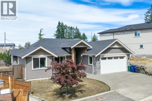 Front view of a modern gray house with a stone-accented entrance and garage door. - 1312 Langara Dr, Nanaimo