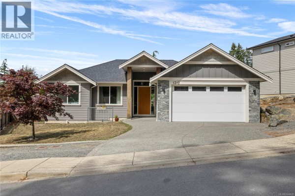 Front exterior view of a single-story gray house with a detached garage and asphalt driveway. - 1312 Langara Dr, Nanaimo