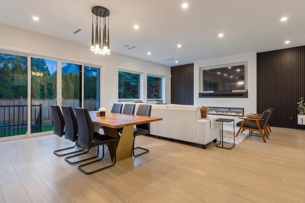 Open concept living and dining area with light wood floors, fireplace, and large windows. - 13125 14 Avenue, Surrey
