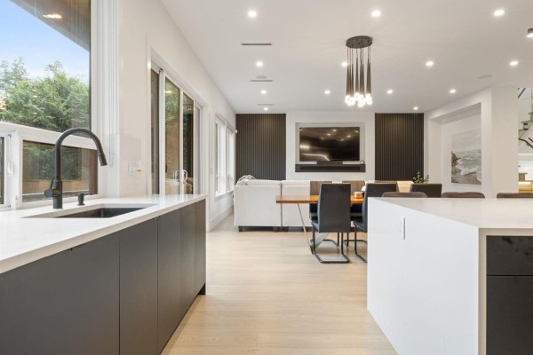 Kitchen island with dark cabinetry and a black faucet, overlooking the dining and living area. - 13125 14 Avenue, Surrey