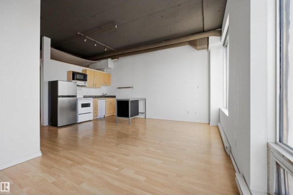 Open concept studio apartment with light wood floors, white walls, a stainless steel refrigerator, oven, and light wood cabinets. - #1313 10024 Jasper Av Nw, Edmonton