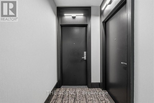 Two dark wood doors in a white hallway with modern lighting fixtures. - 1314 - 438 King Street W, Toronto