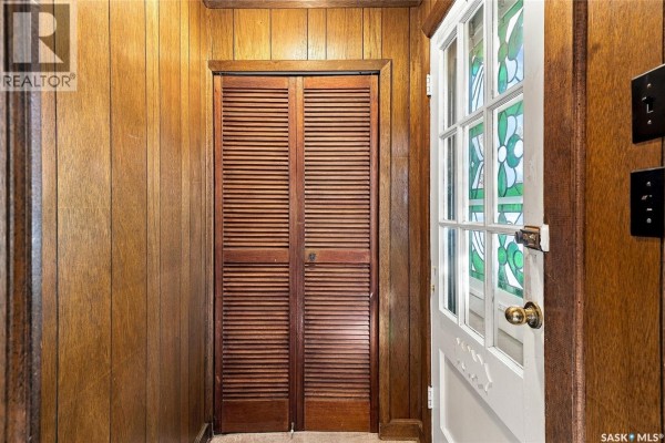 Interior view of a hallway with wood paneling and louvered double doors. - 1315 2nd Avenue N, Saskatoon