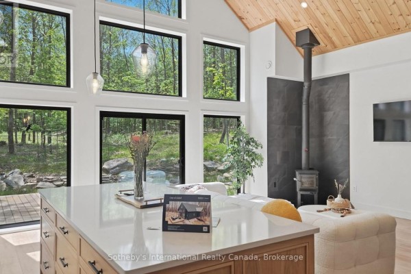 Open concept living area with a modern kitchen, island, sectional sofa, and wood-paneled vaulted ceiling. - 1315 North Drive, Dysart Et Al