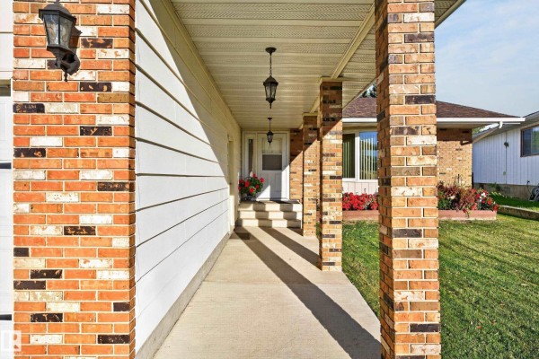 Covered front porch with brick pillars and outdoor lighting leading to the front door. - 1316 85 St Nw, Edmonton