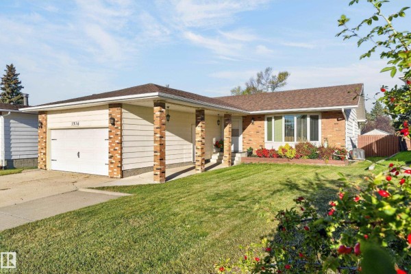 Side view of the brick and siding bungalow with a manicured lawn and flower beds. - 1316 85 St Nw, Edmonton