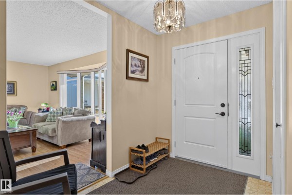 Interior foyer with a white front door, shoe rack, and view into the living room. - 1316 85 St Nw, Edmonton